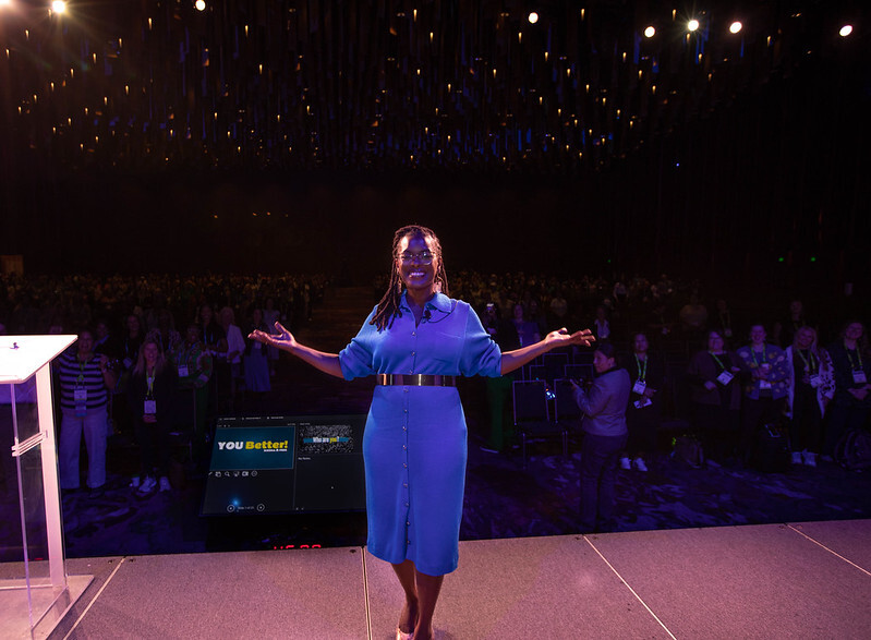 Keisha B. Free on stage at APC 2025; audience in background